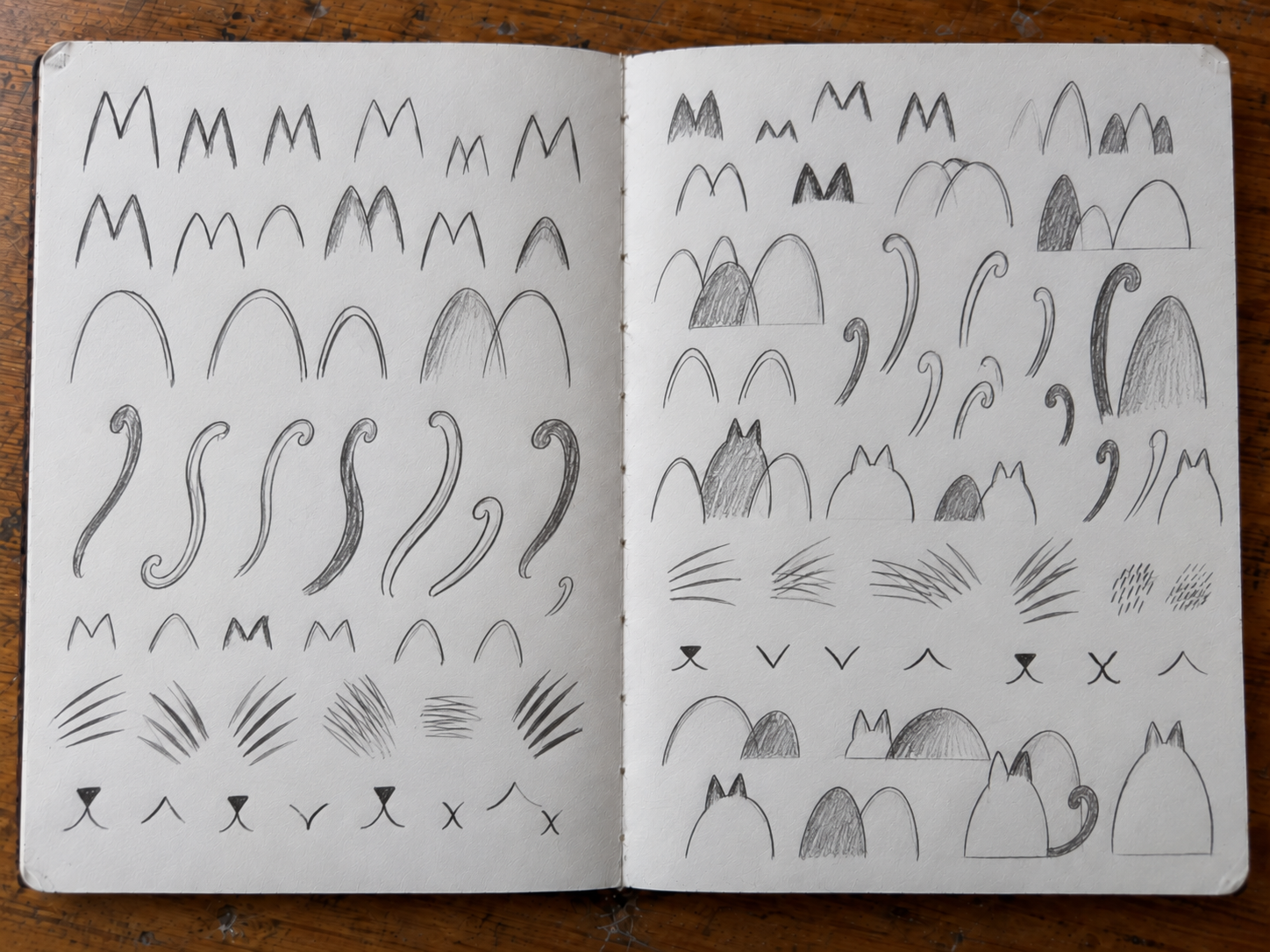 Open sketchbook showing recurring cat-derived marks beginning to combine and behave as a developing visual language.