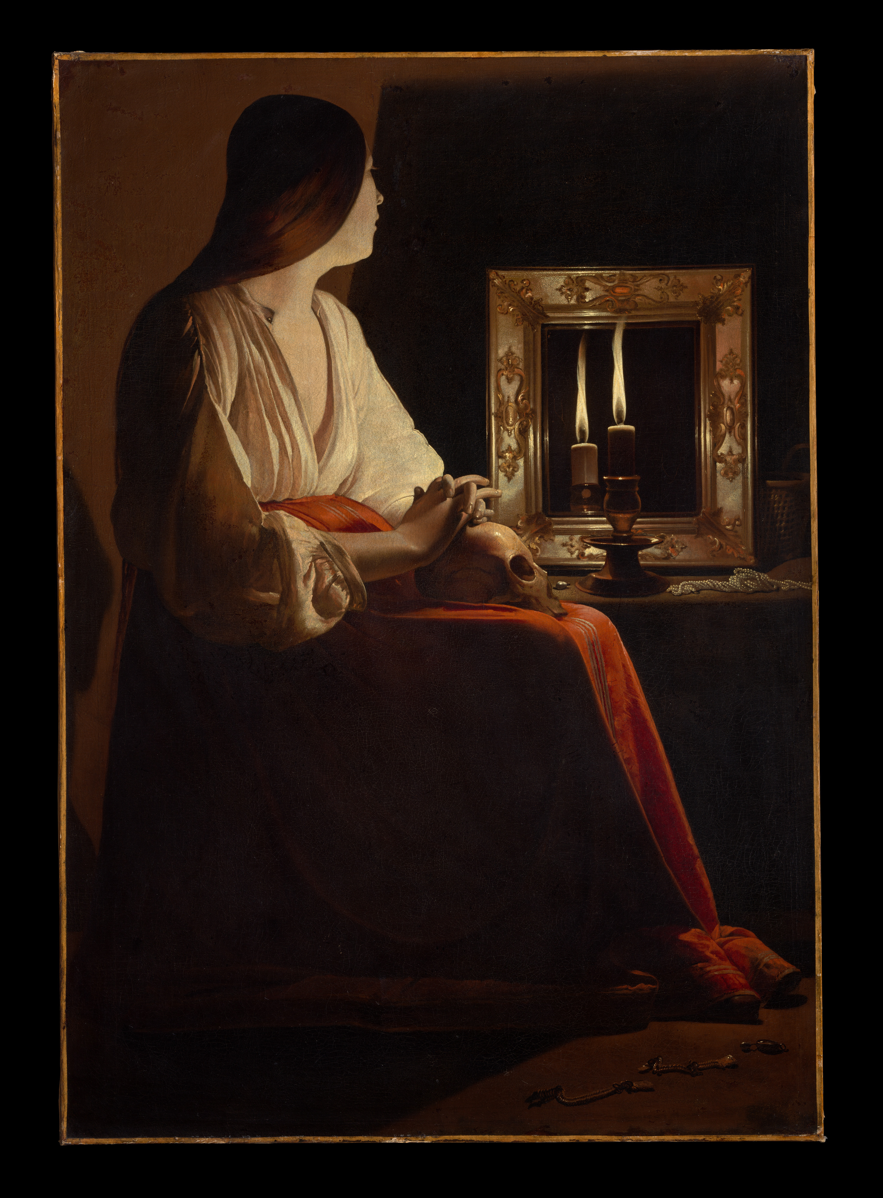 Georges de La Tour, The Penitent Magdalen, ca. 1640. Oil on canvas: a seated woman in a white blouse and red skirt rests her hands on a skull, lit by a single candle standing before a gilt mirror in a dark room.