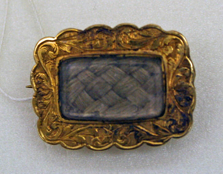 Gold mourning jewellery with glass compartments containing woven hair.