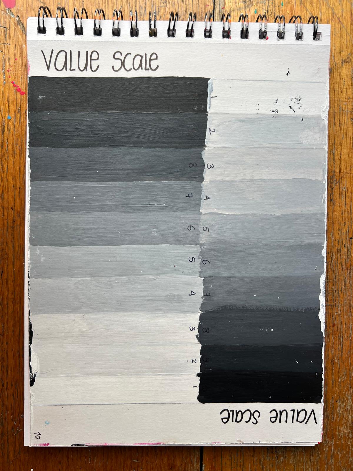 A handmade ten step value scale painted in a spiral sketchbook, moving from black through greys to white, with a handwritten title and numbered steps.